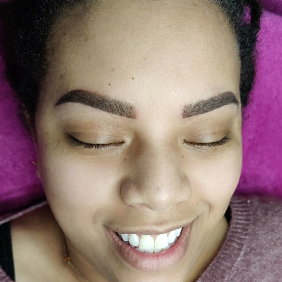 Klant met donkere ombrébrows, lachend op de behandelstoel